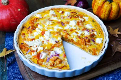 Goldene Kürbis-Quiche mit Hokkaidokürbis, Feta und frischen Kräutern, angerichtet für den Herbsttisch