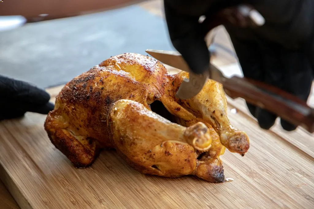 Grillhaehnchen tranchieren auf Holzbrett