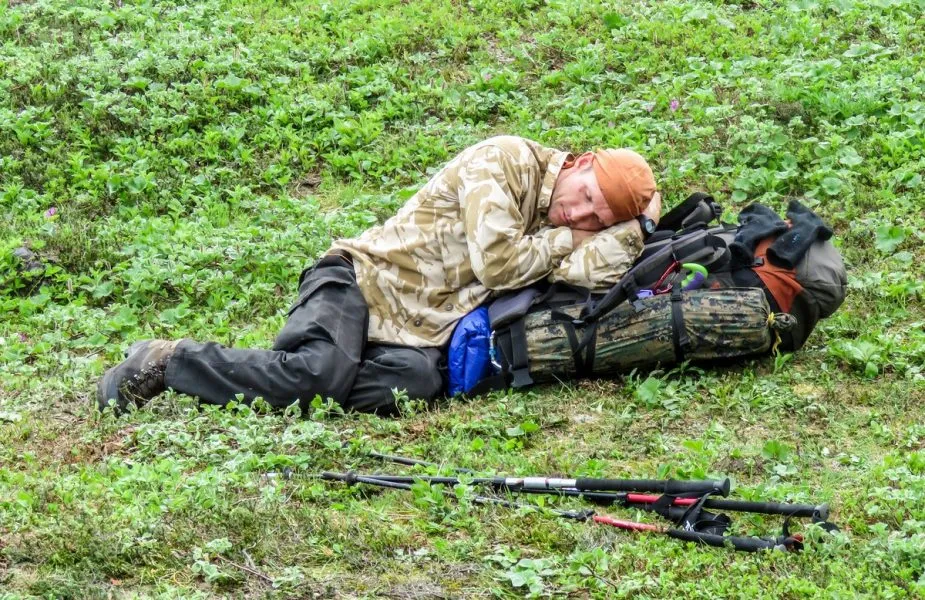 Gruppenmitglied schläft erschöpft auf dem felsigen Boden während der Expedition