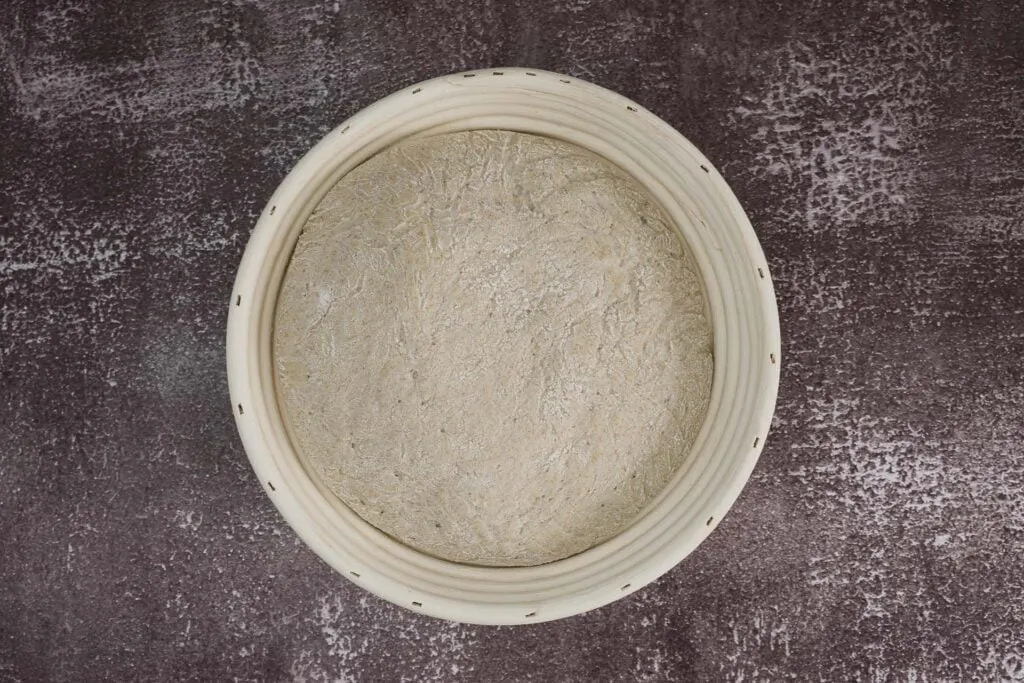 Hände kneten geschickt den Teig für ein selbstgemachtes veganes Bauernbrot, ein wichtiger Schritt für die perfekte Textur.