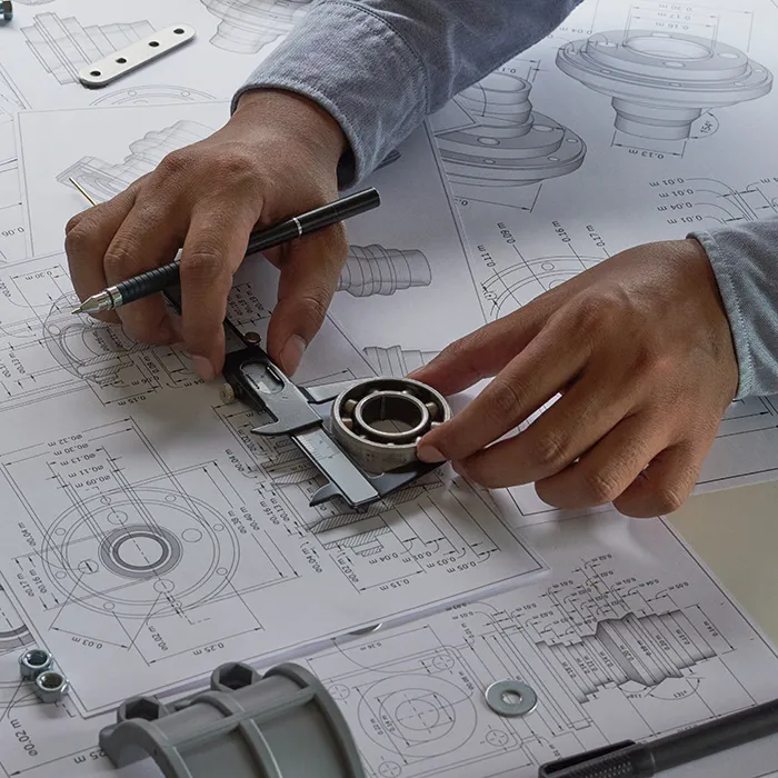 Hände zeichnen technische Pläne mit Lineal.