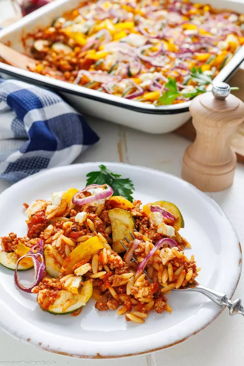 Herzhafter Kritharaki-Auflauf mit goldbraunem Feta und frischem Gemüse, bereit zum Servieren