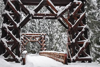 Historische Holzbrücke, sanft mit frischem Schnee bedeckt, bietet einen malerischen Anblick in einer winterlichen Landschaft.