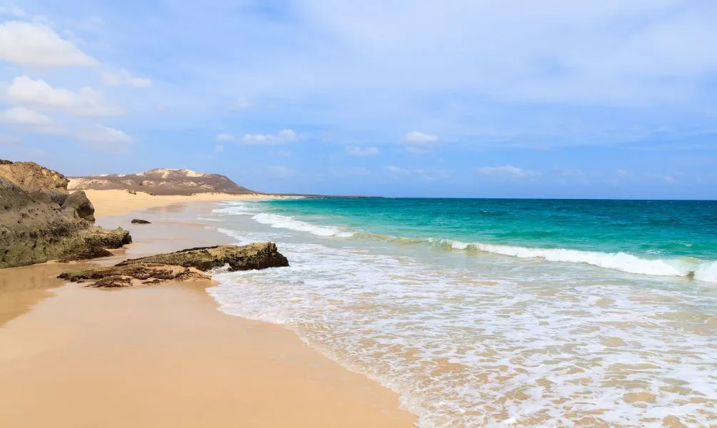 Idyllischer Strand auf einer der Kapverdischen Inseln mit goldenem Sand und blauem Meer.
