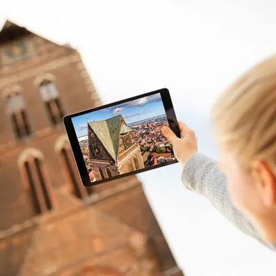 Interaktiver Stadtrundgang mit einem Tablet, eine Person hält ein Tablet mit einer Karte in der Hand