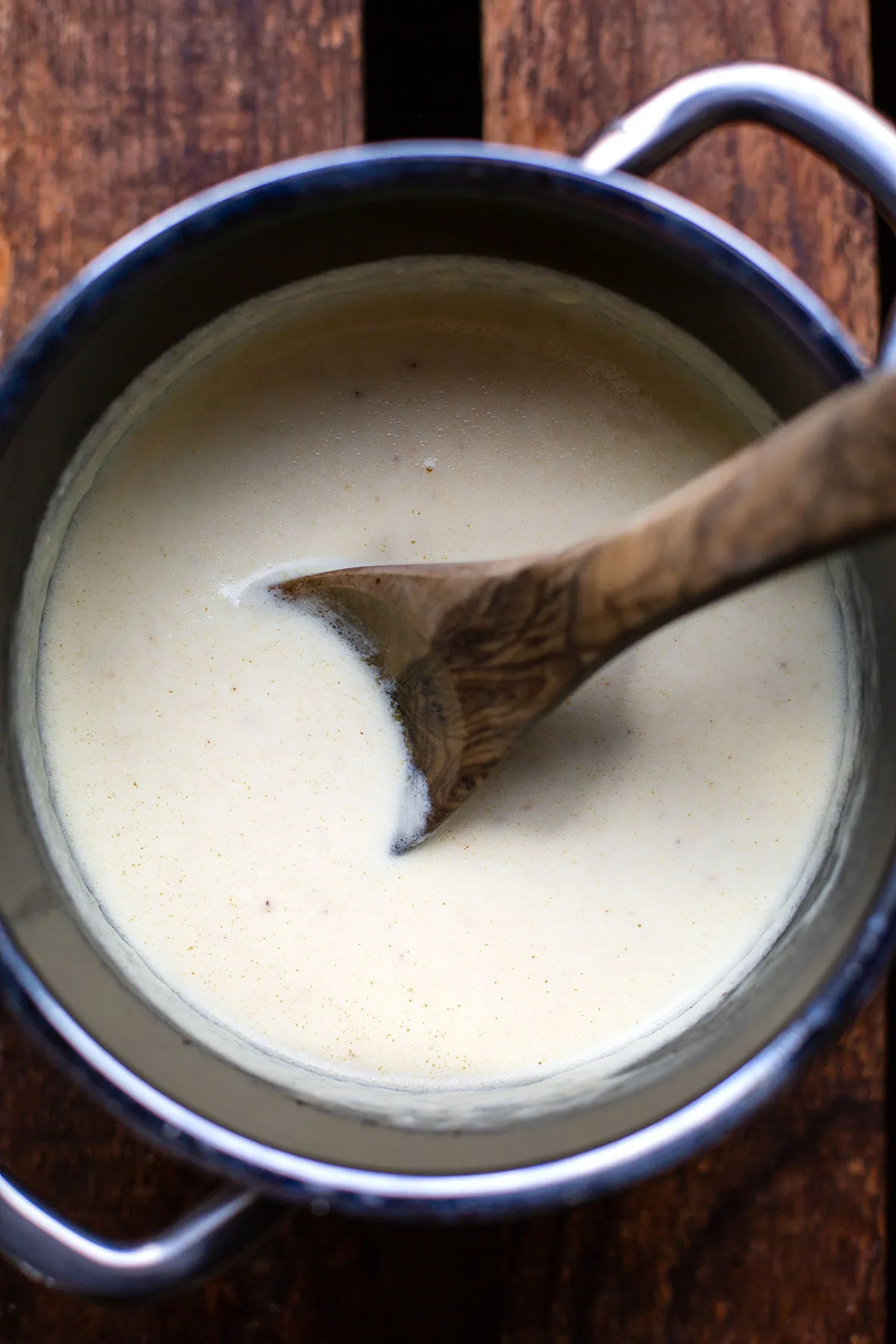 Käse-Sahne-Soße im Topf mit Kochlöffel