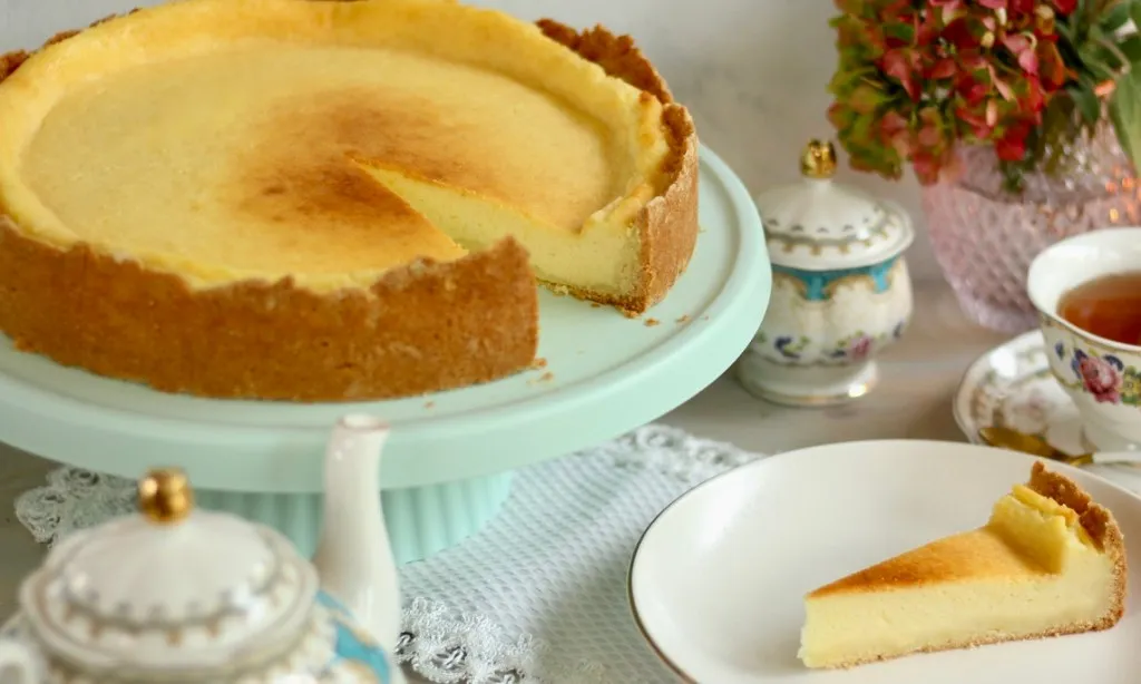 Käsekuchen auf einem Kuchenteller mit Puderzucker bestäubt