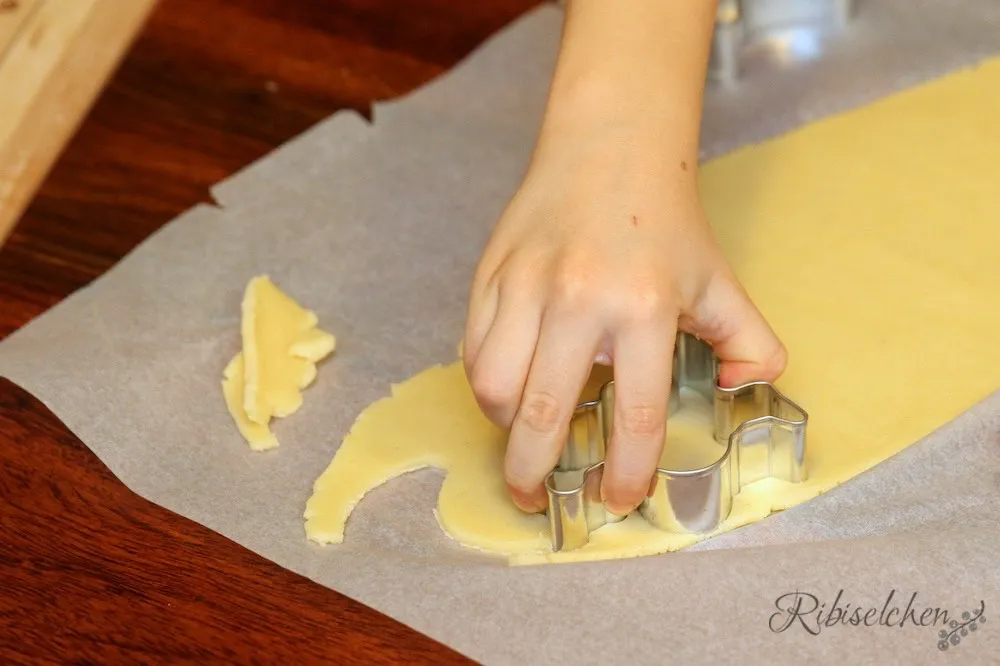 Kinderhände stechen Sterne aus Keksteig