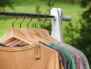 Kleidungsstücke hängen an einer Stange, symbolisieren nachhaltige Mode