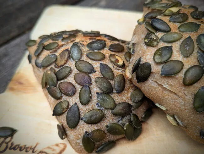 Kürbiskerne werden als Topping auf die Brötchenrohlinge aufgebracht