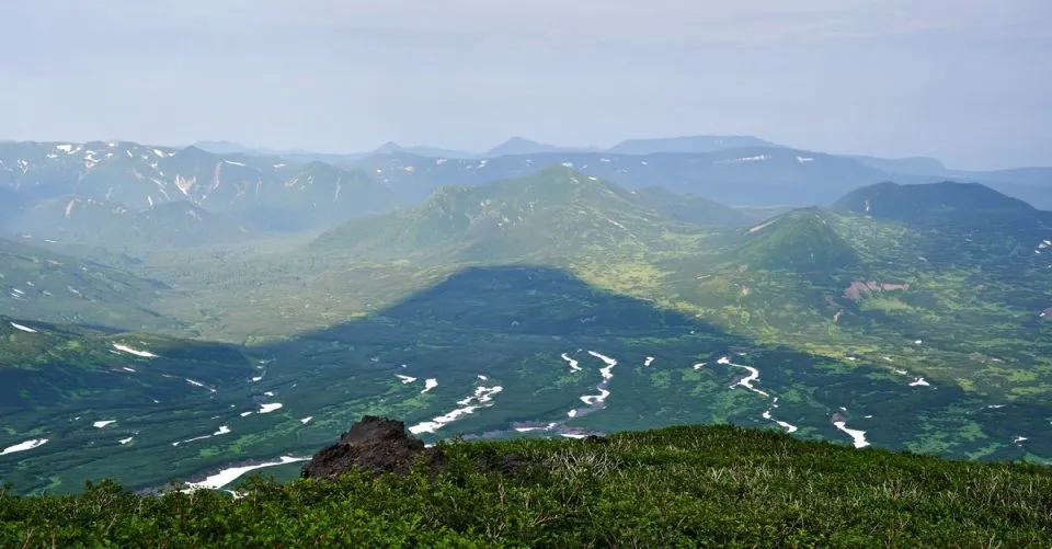 Langer Schatten des Kambalny Vulkans bei Sonnenuntergang über Kamtschatka