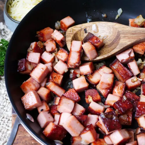 Leberkäsewürfel und Zwiebeln werden in einer Pfanne angebraten
