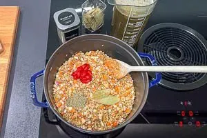 Linsen, Gemüse und Tomatenmark anbraten und mit Brühe aufgießen