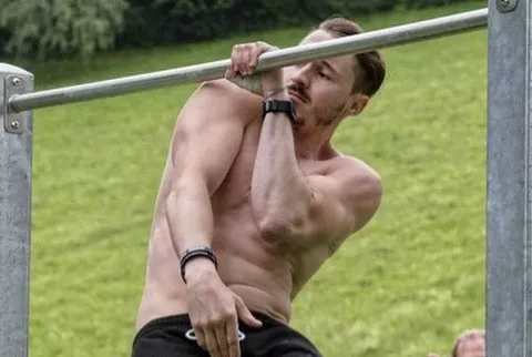 Mann führt einen einarmigen Klimmzug an einer Stange aus