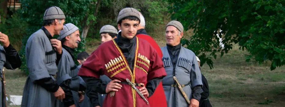 Männer und Frauen in traditionellen georgischen Trachten, die ein festliches Gelage genießen und ihre Gastfreundschaft zelebrieren