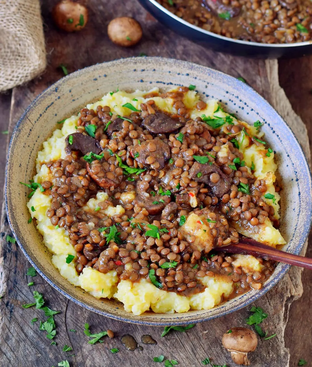 Mashed potatoes in a bowl with lentil stew and mushrooms.