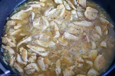 Mehl und Currypulver werden über das Hähnchen in der Pfanne gestreut