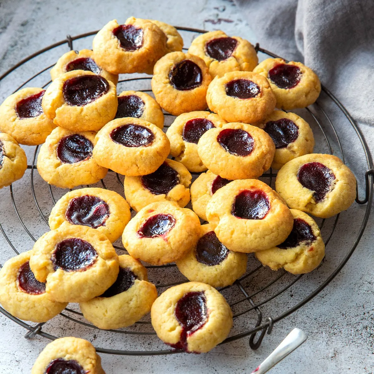 Mehrere Marmeladenplätzchen auf einem Holztisch, im Hintergrund unscharf weitere Kekse