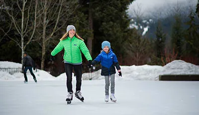 Menschen laufen Schlittschuh auf einer beleuchteten Eisfläche unter freiem Himmel