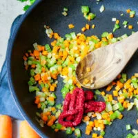 Möhren- und Selleriewürfel und Tomatenmark in der Pfanne werden angedünstet, die Basis für eine aromatische Linsen Bolognese.