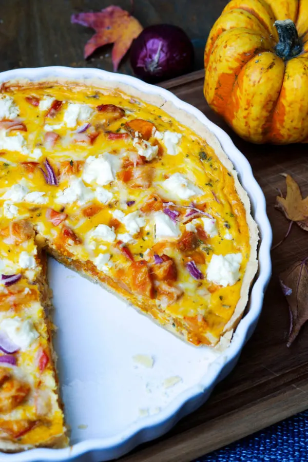 Nahaufnahme einer fertig gebackenen Kürbis-Quiche mit goldbrauner Kruste, Kürbiswürfeln und Feta