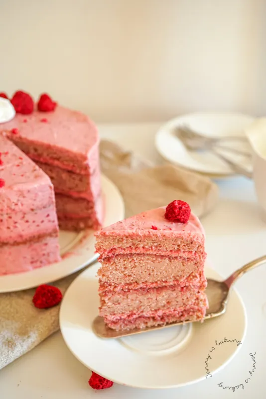 Nahaufnahme einer rosa Torte von der Seite, mit glatter Creme und Himbeeren