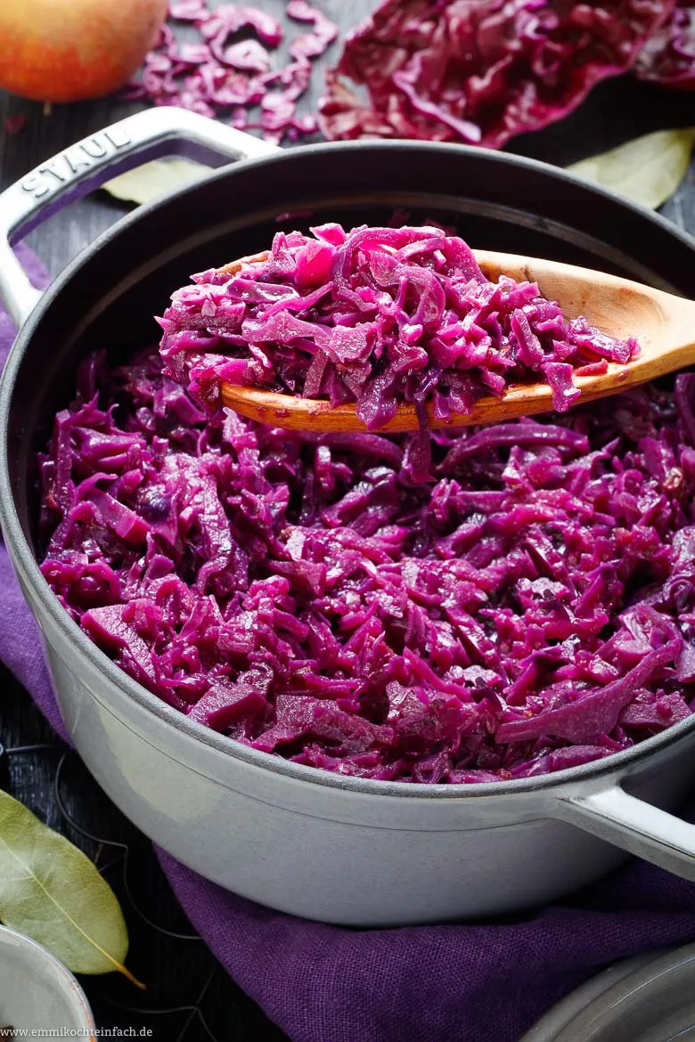 Nahaufnahme einer Zwiebel, gespickt mit Nelken, in einem Topf voller Rotkohl