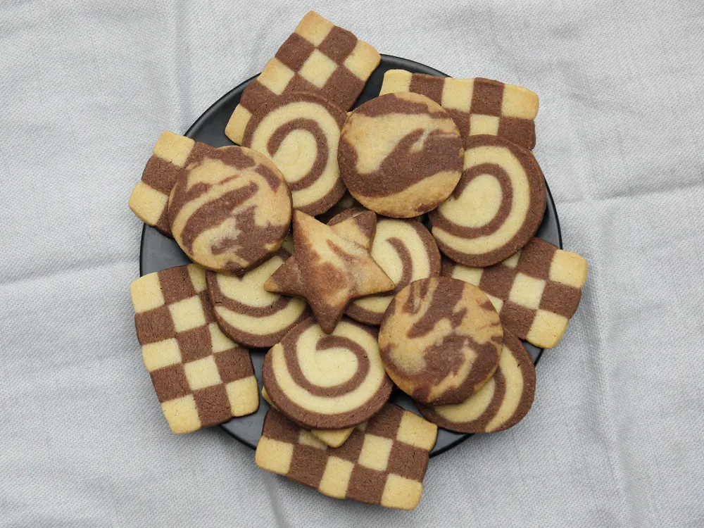 Nahaufnahme von fertig gebackenem Schwarz-Weiß-Gebäck mit verschiedenen Mustern auf einem Teller