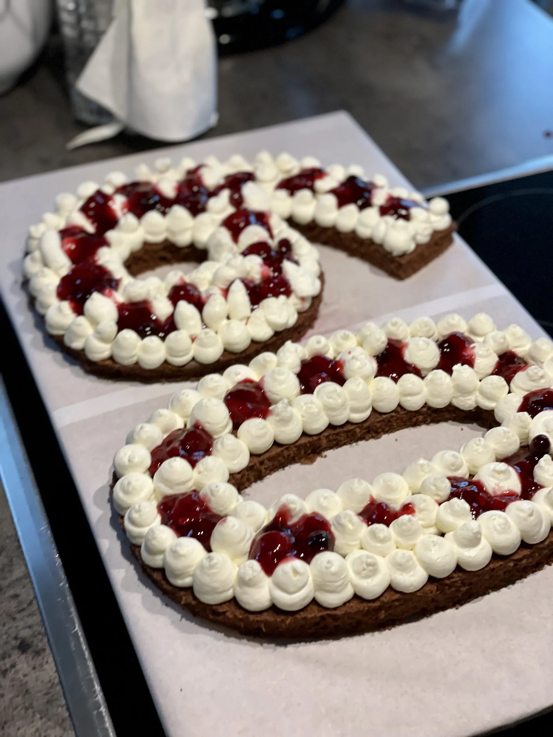 Nahaufnahme von roten Beeren, die als Füllung auf einer Schicht Creme auf dem Number Cake verteilt werden