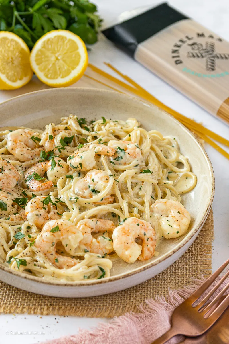 Nahaufnahme von Spaghetti in einer hellen Käsesauce mit frisch gebratenen Garnelen und Petersilie