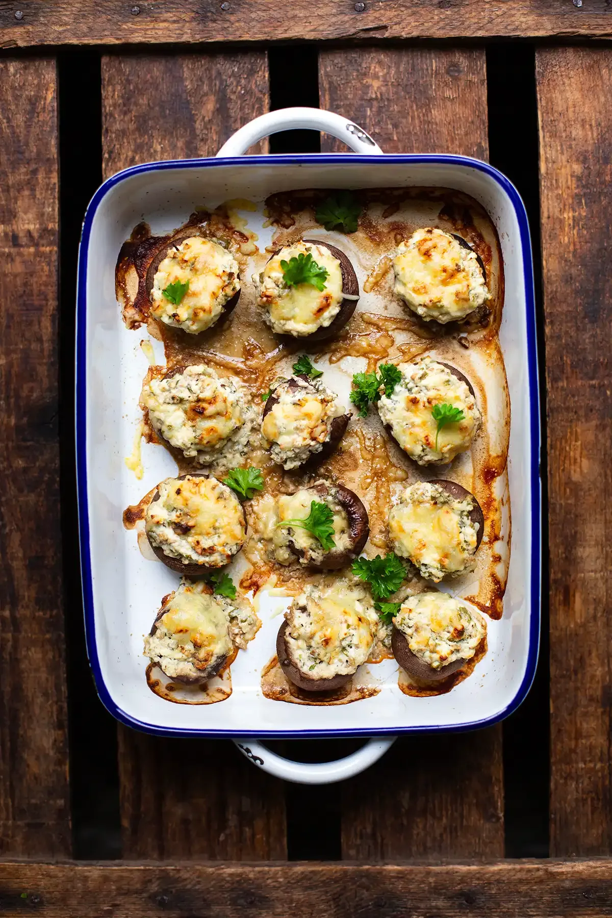 Perfekt gebackene gefüllte Champignons mit goldbrauner Käsekruste in einer weißen Auflaufform