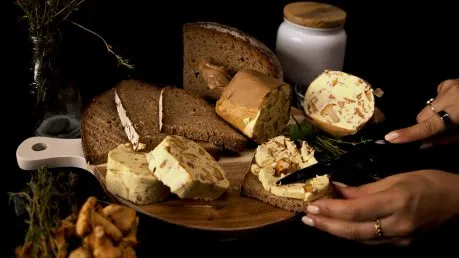 Reichhaltige Pilzbutter mit Pfifferlingen auf einem Teller, daneben Brot