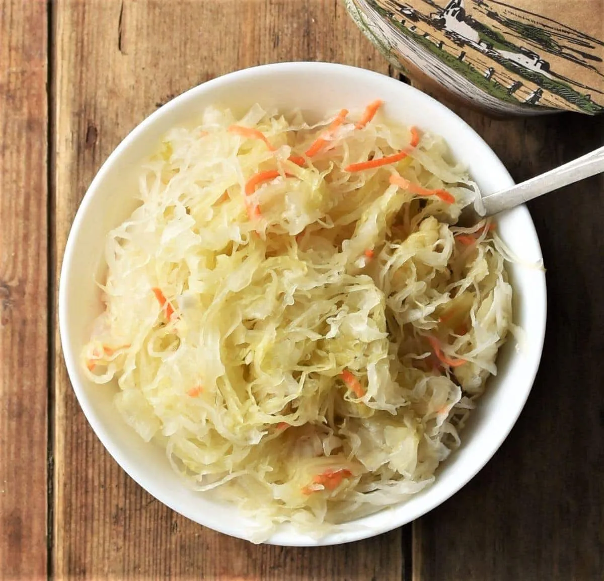Sauerkraut in einer weißen Schüssel mit einem Löffel zum Servieren bereit.