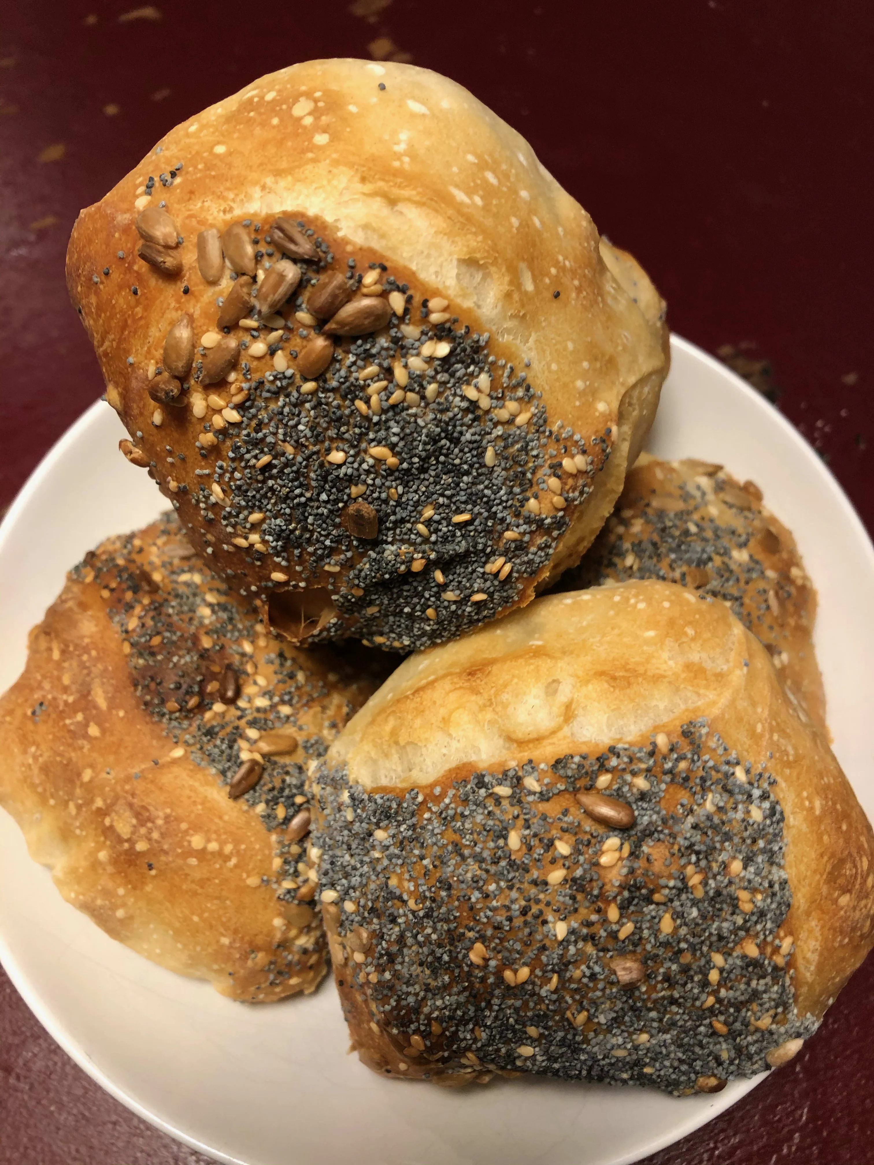 Selbstgemachte Sonntagsbrötchen mit verschiedenen Saaten, auf einem Backblech angerichtet