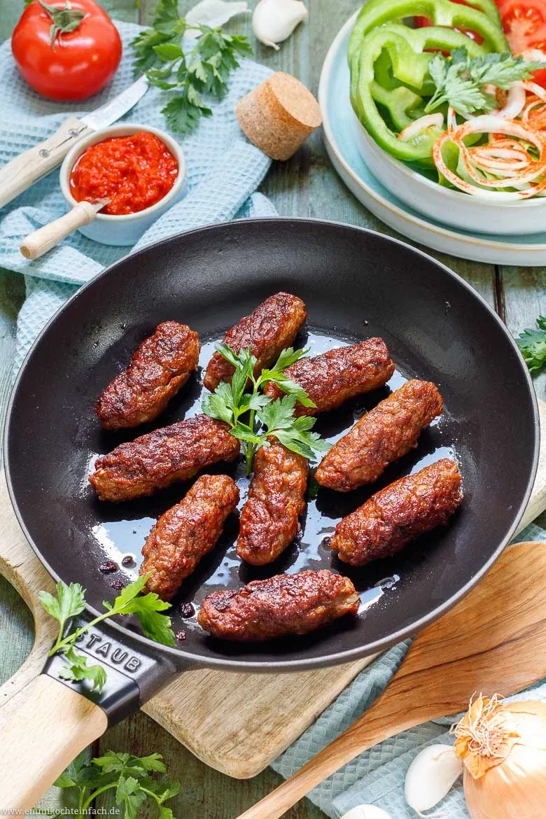 Servierte Cevapcici mit Ajvar, Zwiebeln und Tomaten, bereit zum Genießen, ein wahrer Balkan-Klassiker