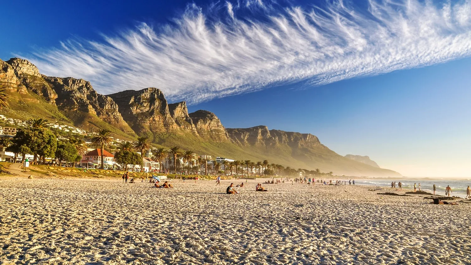 Sonniger Strand bei Camps Bay in Kapstadt mit den majestätischen Zwölf Apostel Bergen im Hintergrund, ideal für einen warmen Urlaub im März