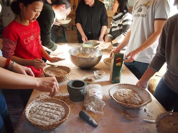 Teilnehmer eines Brotbackkurses lernen traditionelle Backtechniken in einer rustikalen Backstube