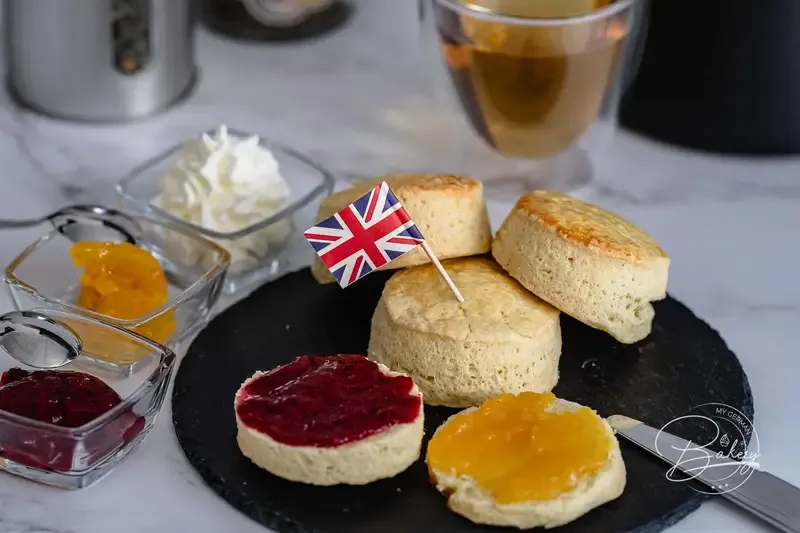 Teller mit frisch gebackenen englischen Scones, dazu Erdbeermarmelade und Clotted Cream