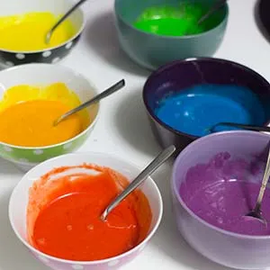 Verschiedene Schüsseln mit eingefärbtem veganem Kuchenteig in den Regenbogenfarben