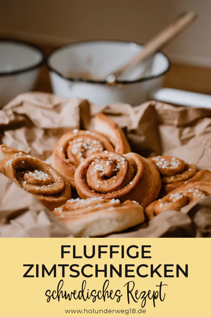 Vertikale Ansicht von mehreren perfekt gebackenen, fluffigen schwedischen Zimtschnecken auf einem Rost, bestreut mit Hagelzucker.