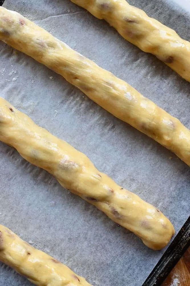 Vier ungebackene Teigrollen auf Backpapier von oben