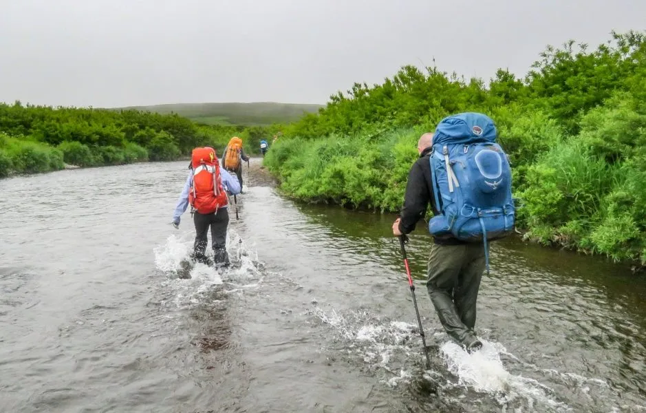 Wanderer bahnen sich den Weg durch felsige Bachläufe in Kamtschatka