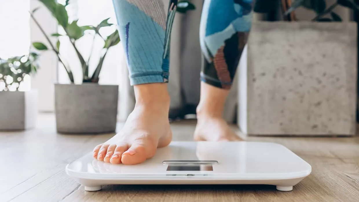 Weibliche Füße, die auf eine Waage steigen