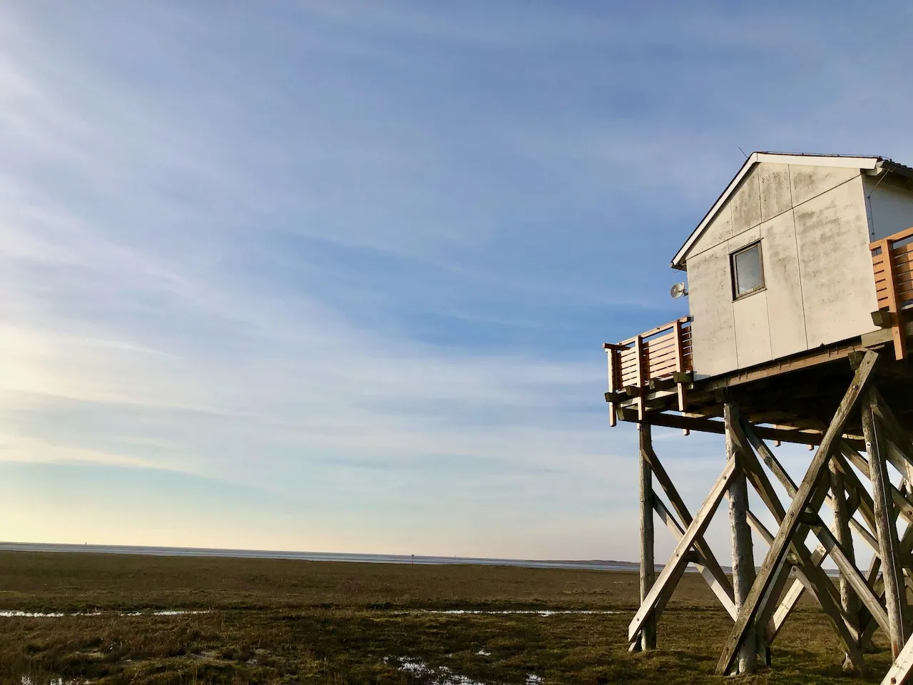 Weitläufiger Sandstrand von St. Peter Ording mit typischen Pfahlbauten und dem Meer bei Ebbe