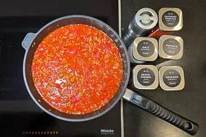 Würzen der Hackfleischsoße mit Oregano, Salz, Paprikapulver, Kreuzkümmel, Pfeffer und Cayennepfeffer für den mediterranen Geschmack