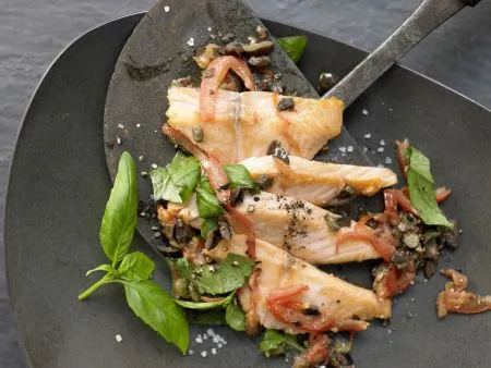 Zartes Lachsfilet auf Tomatengemüse mit schwarzen Oliven und frischem Basilikum, reich an Omega-3-Fettsäuren