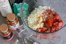 Zutaten für Cevapcici in einer Schüssel: Hackfleisch, Zwiebeln, Knoblauch und Gewürze werden vermengt