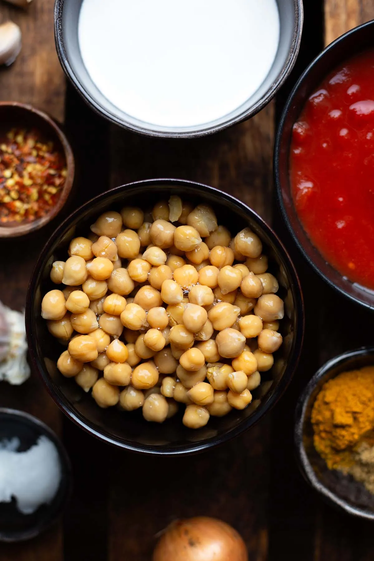 Zutaten für Kichererbsen-Curry in Schüsseln: Kichererbsen, gehackte Tomaten, Kokosmilch, Gewürze, Zwiebel & Knoblauch und Kokosöl