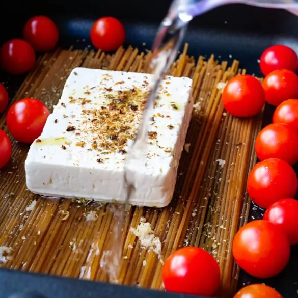 Zutaten für Spaghetti mit Feta und Tomaten in einer schwarzen Auflaufform, bevor Wasser hinzugefügt wird