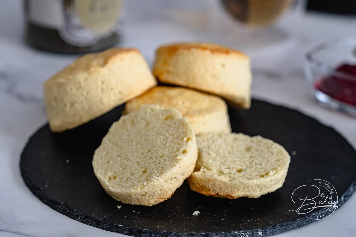 Zwei aufgeschnittene Scones mit aufgetragenem Fruchtaufstrich, bereit zum Genießen